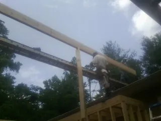 Carpenter setting a ridge beam over a new addition frame — Ice Dam Removal by Roofing Brothers in Cummington