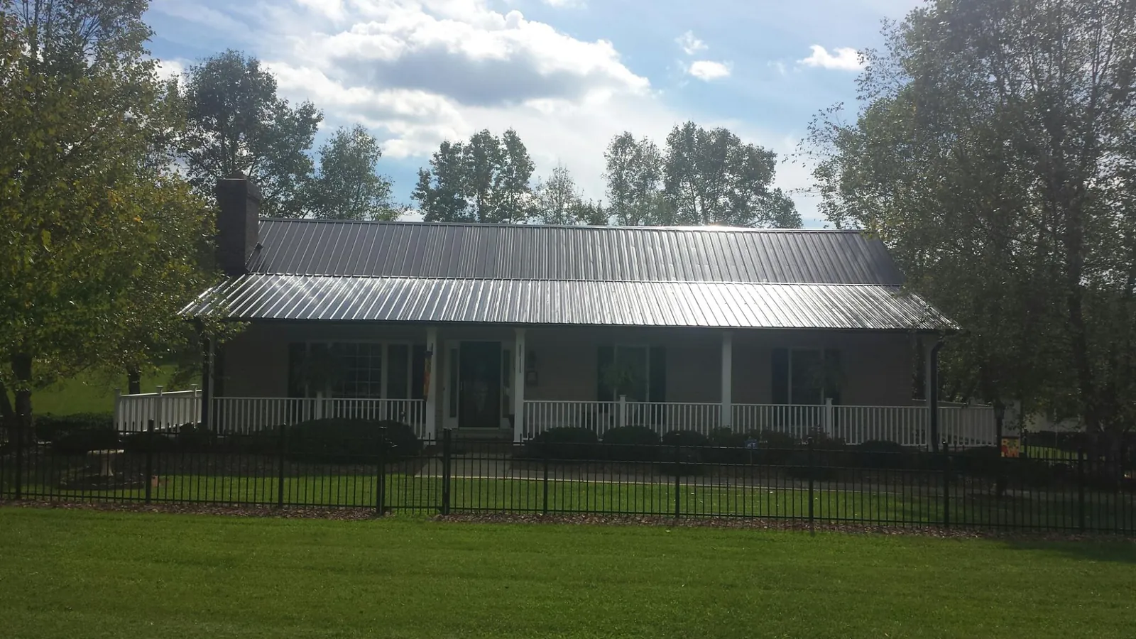 Gray metal roof on a brick ranch with a full width front porch — Gutter Guard Installation work by our crew in Cummington