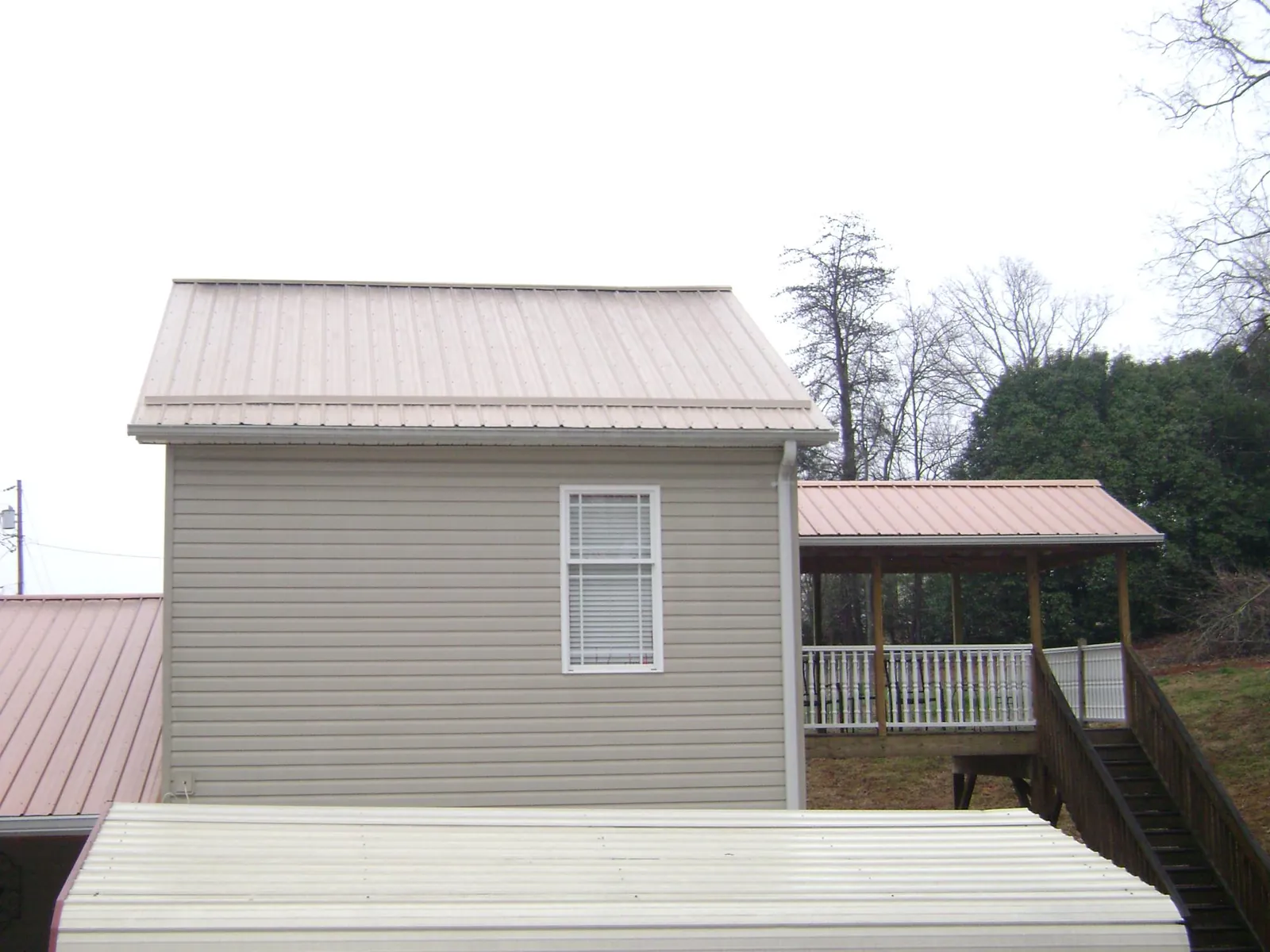 Tan metal roofs on a two story addition and attached porch, from a Roof Replacement job in Cummington